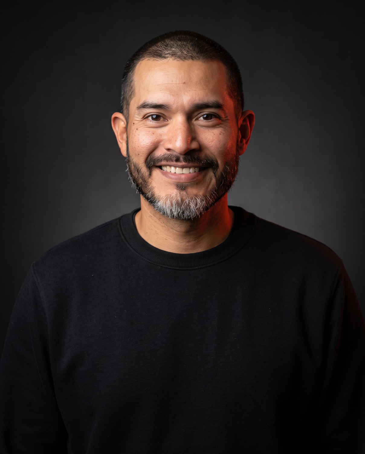 Professional studio portrait of Chuck Serna, bearded and without a cap.