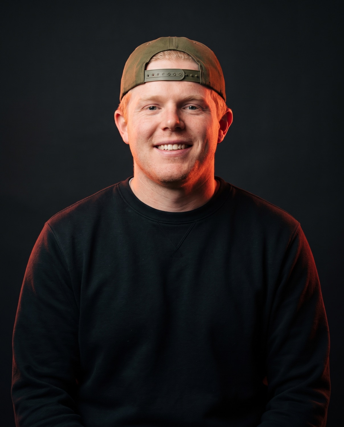 Professional studio portrait of Eddie Lee Marburger smiling in a backward cap.