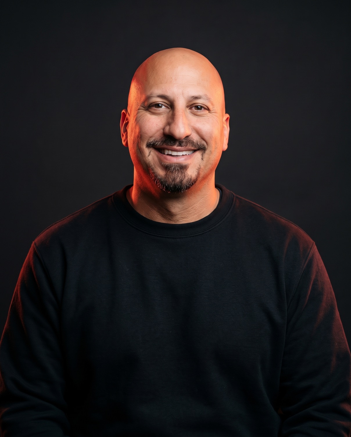Professional studio portrait of Hernan Mireles, bald with a goatee.
