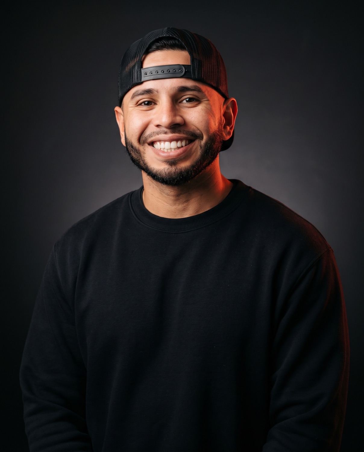 Professional studio portrait of Jerry Gonzalez smiling in a backward black cap.