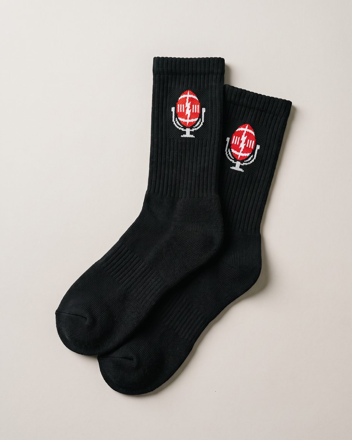 Black crew socks laid flat with the football-mic emblem on the cuffs